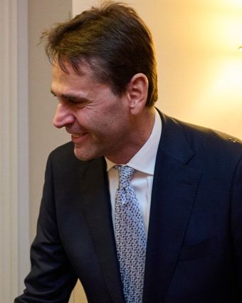 Christophe Fouquet smiling, in a dark suit and patterned tie