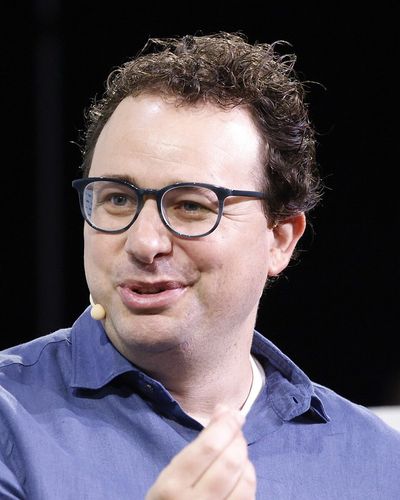 Dario Amodei in glasses and a blue shirt, speaking