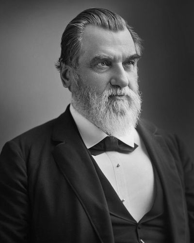 Leland Stanford in 1890, with a full white beard, in a dark suit and bow tie