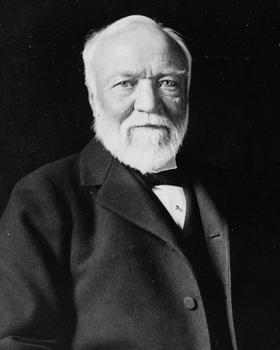 Andrew Carnegie with white hair and a white beard, in a dark suit