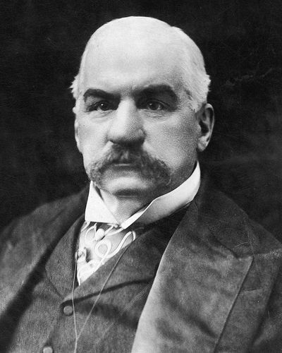 J. P. Morgan in 1902, with a heavy moustache, in a dark suit and wing collar
